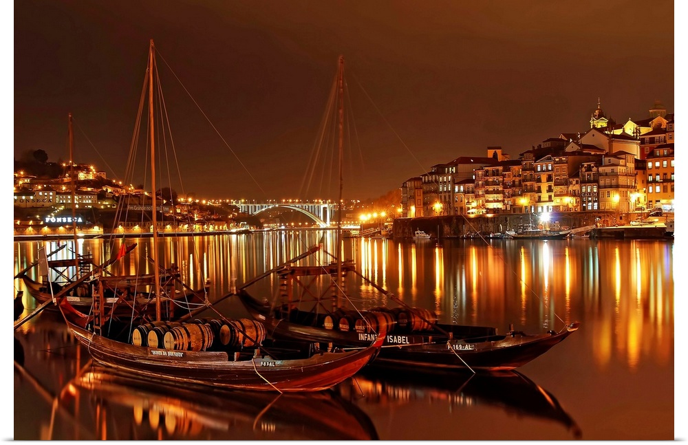 Boats in the River Douro in Porto illuminated with city lights at night.
