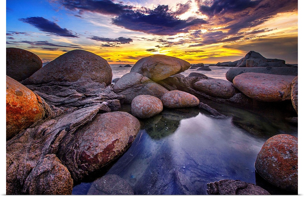 Beautiful sunset colors and dramatic clouds over a rocky beach.