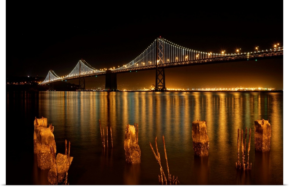 The Bay Bridge in San Francisco lit up at night, as seen from the shore.