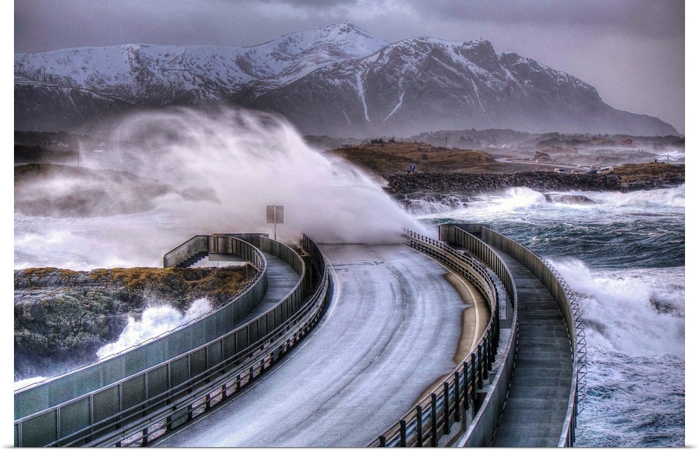 Waves crashing over a road as a car speeds away from a coming storm, Norway.