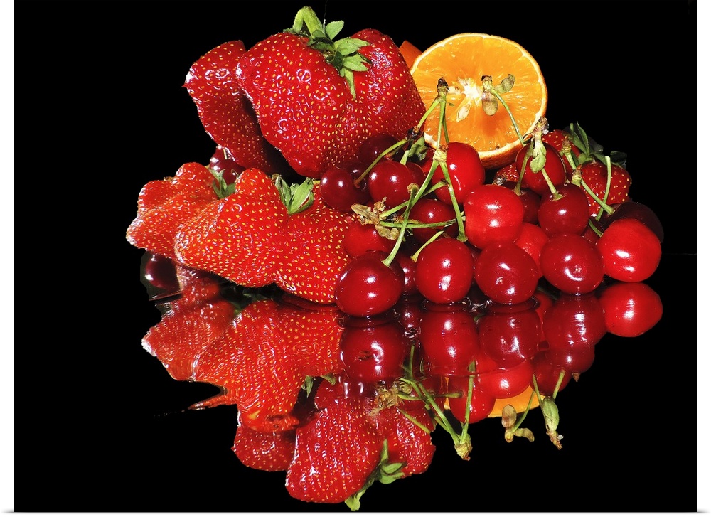 A group of red fruits including strawberries, cherries, and a slice of orange, on a mirror.