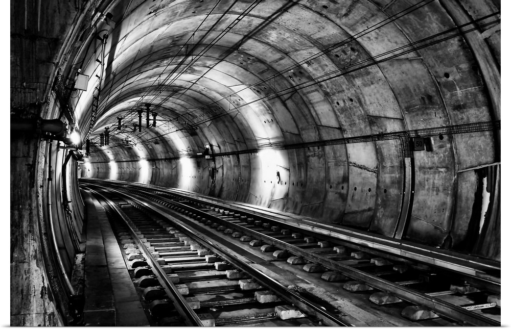 Train tracks in an underground tunnel, in black and white.