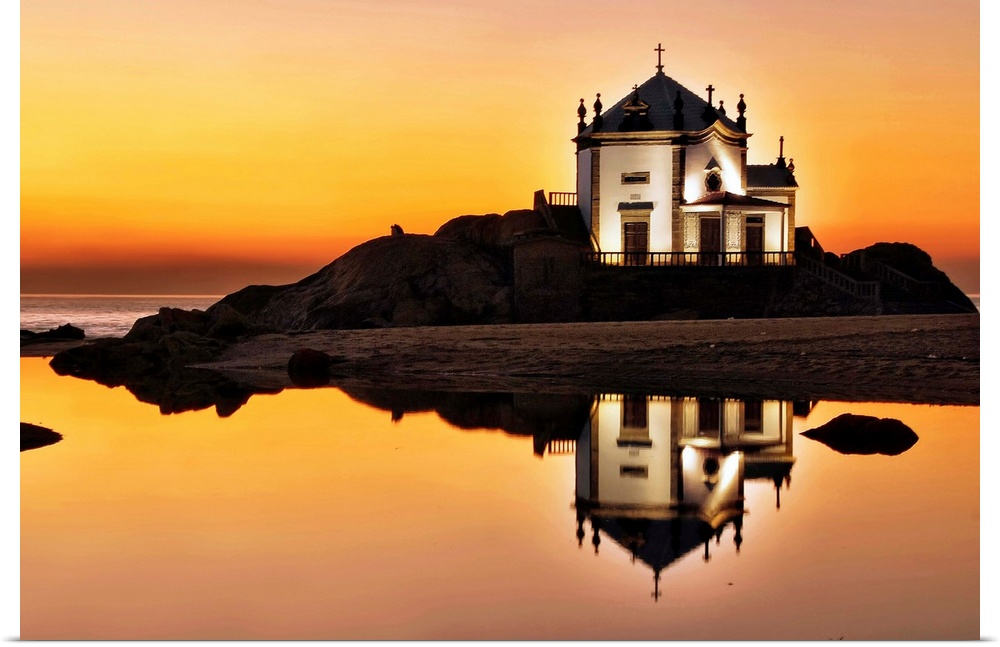 A chapel on an island at sunset, with a mirror reflection in the water below.