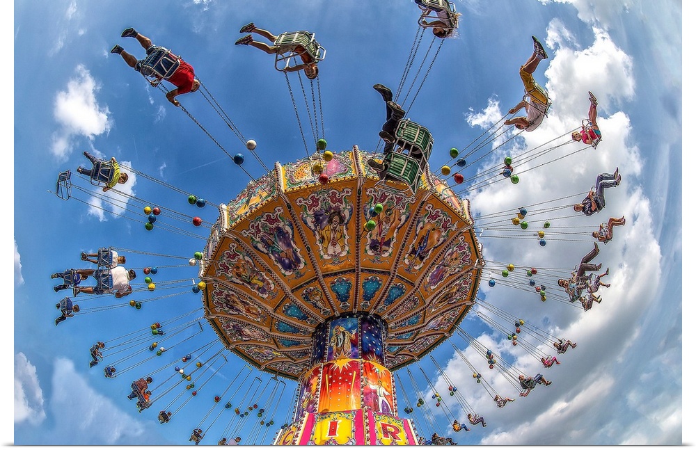 An amusement park ride with people on swings, under a blue sky.