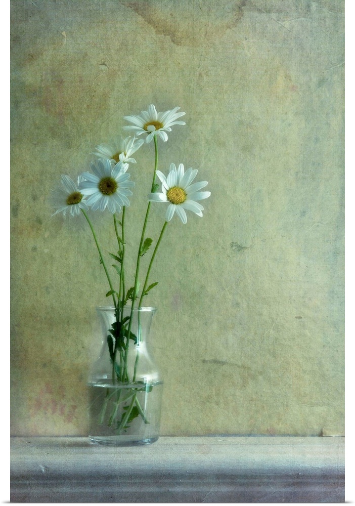 A little glass vase with five daisy flowers on a wooden shelf