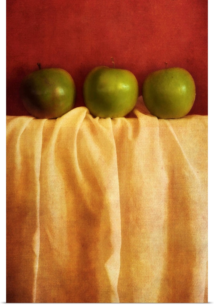 Still life with three granny smith apples against red background