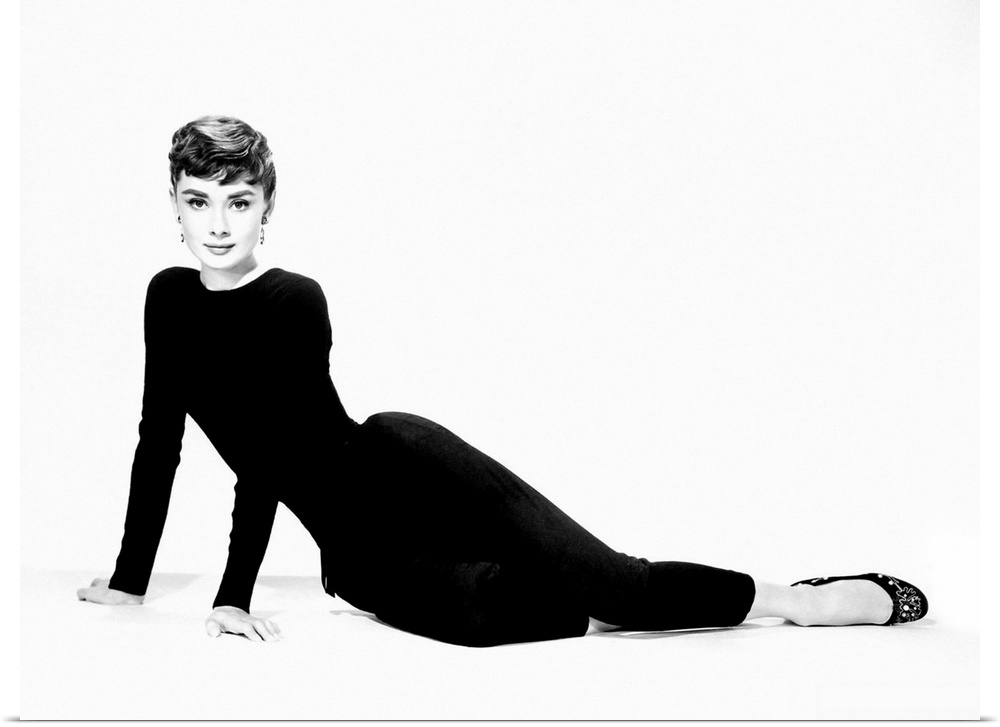 A large piece of artwork in black and white of Audrey Hepburn sitting on her hip and both arms stretched out to support he...