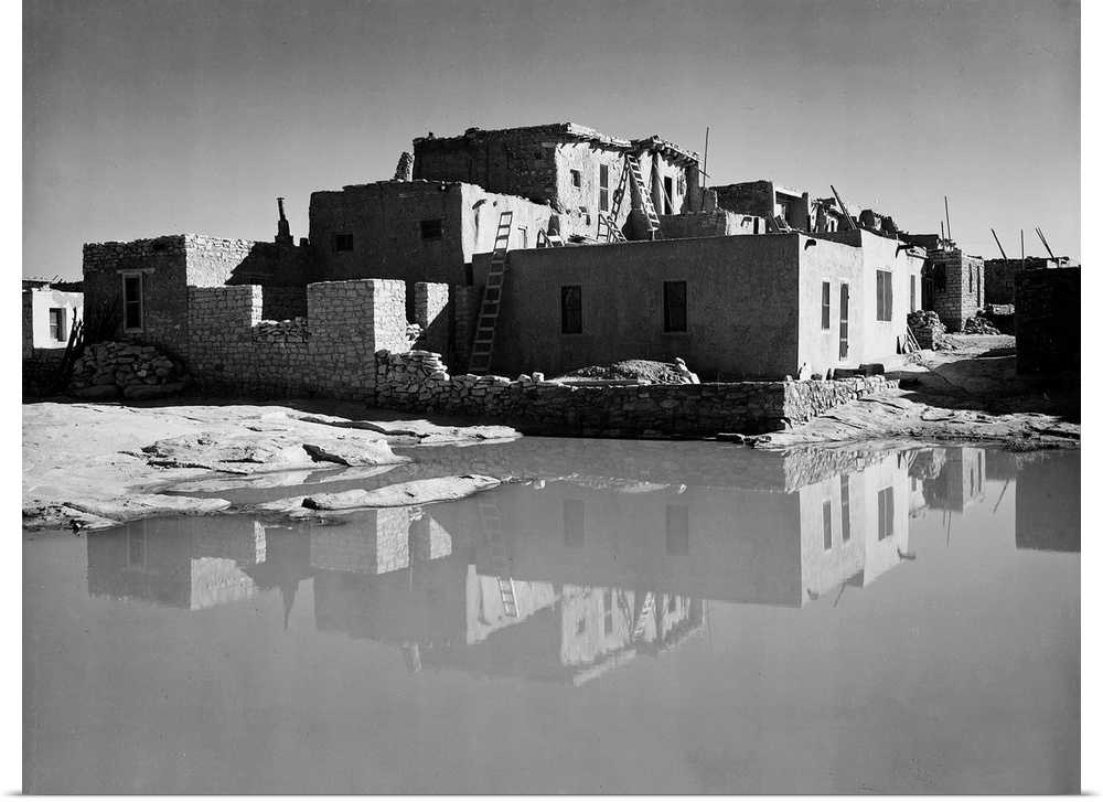Acoma Pueblo, New Mexico, full side view of adobe house with water in foreground.