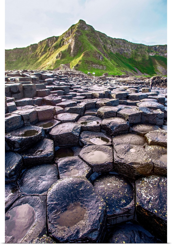 Landscape photograph of the basalt columns on Giant's Causeway with rocky hills and in the background.