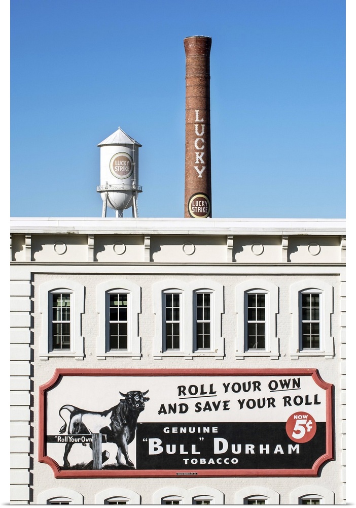 Bull Durham tobacco advertisement on a building facade, Lucky Strike water tower and smokestack in the distance, Durham, N...
