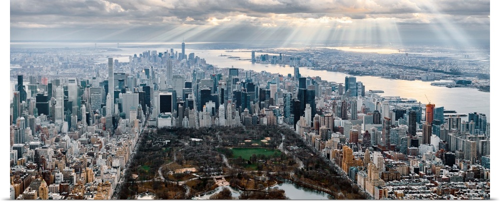 Panoramic view of Central Park in New York City, surrounded by skyscrapers, under a cloudy sky.
