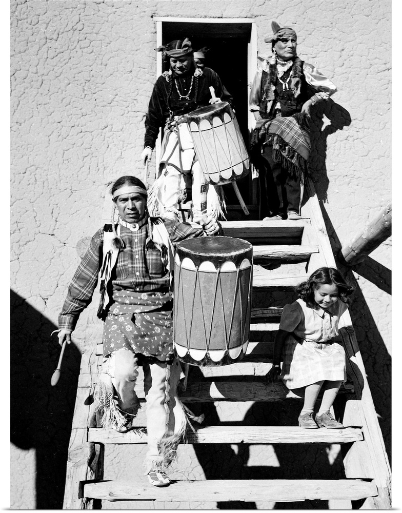 Dance, San Ildefonso Pueblo, New Mexico, 1942, two Indians descending wooden stairs, carrying drums; another Indian and ch...