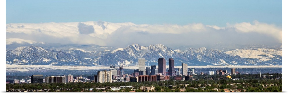 Panoramic photo of a Denver skyline against a backdrop of the Rocky Mountains.