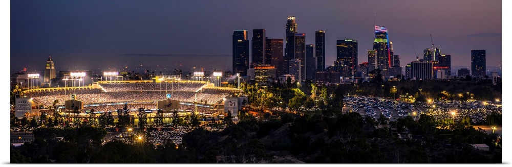 Panoramic photograph of Dodger Stadium lit up on a game night with the Los Angeles skyline on the right.