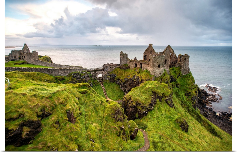 Landscape photograph of Dunluce Castle next to the ocean, taken from a higher point.