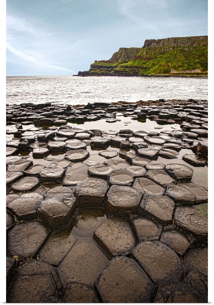 Landscape photograph of the basalt columns on Giant's Causeway with rocky cliffs and the Atlantic Ocean in the background.