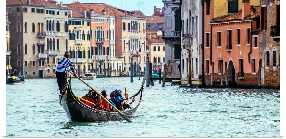 Photograph of the rear side of a gondola rowing through Grand Canal in Venice.