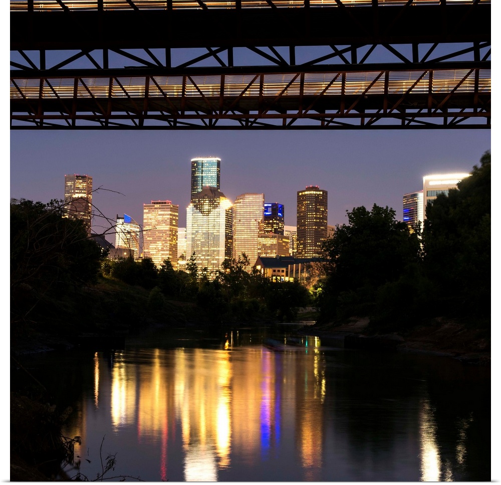 Square photograph of the Houston TX skyline at night reflecting into the Buffalo Bayou with the Rosemont Pedestrian Bridge...