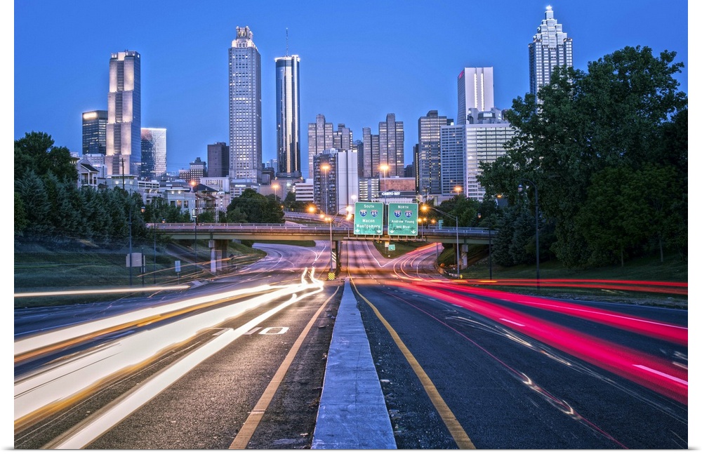 Bright light trails from traffic on the freeway, headed towards the Atlanta, Georgia skyline at twilight.