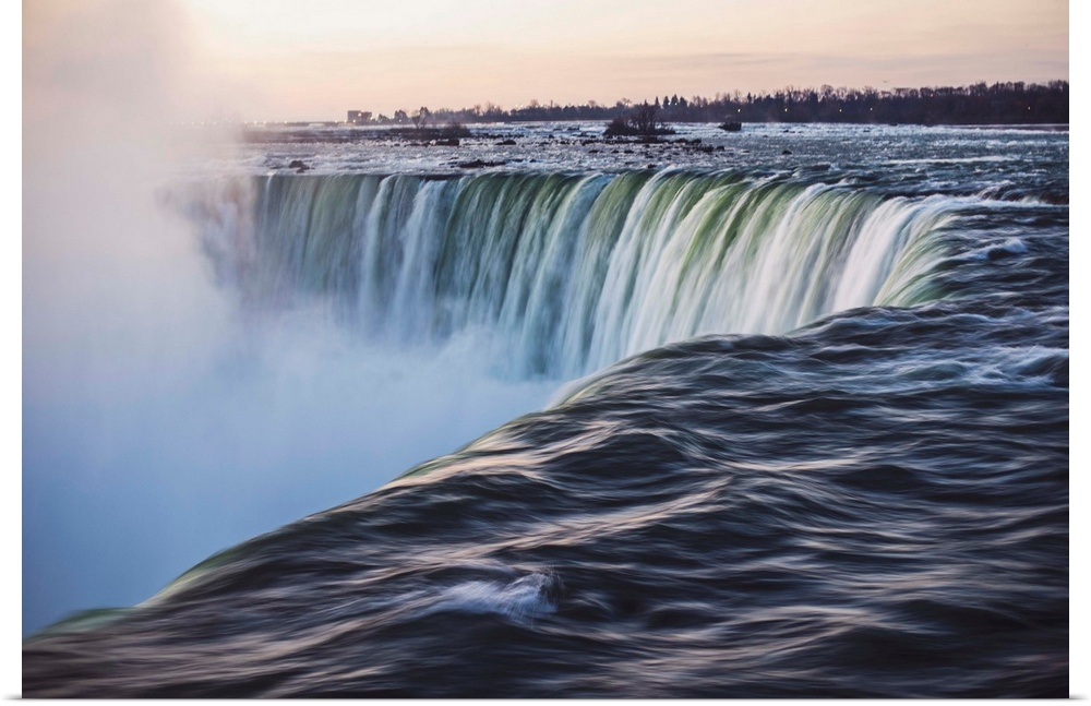 Water cascades down at Horseshoe Falls while dramatic mist ascents to meet the rising sun.