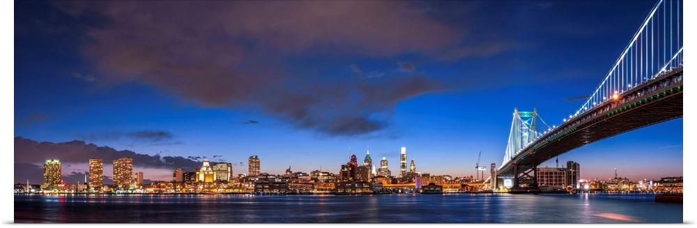 Panoramic view of Philadelphia city skyline at night with Ben Franklin Bridge.