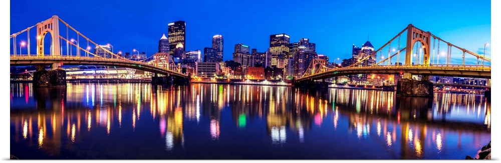 Panoramic photo of downtown Pittsburgh at night with the Rachel Carson Bridge and the Andy Warhol Bridge over the Alleghen...