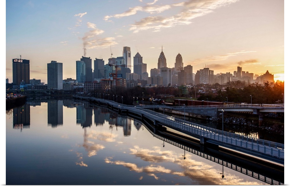 The sun rises above Philadelphia's city skyline with the sky reflecting on the Delaware river.