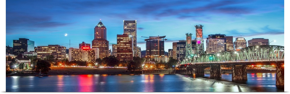 Panoramic photograph of a saturated Portland, Oregon skyline at sunset reflecting onto the Willamette River with a moon in...