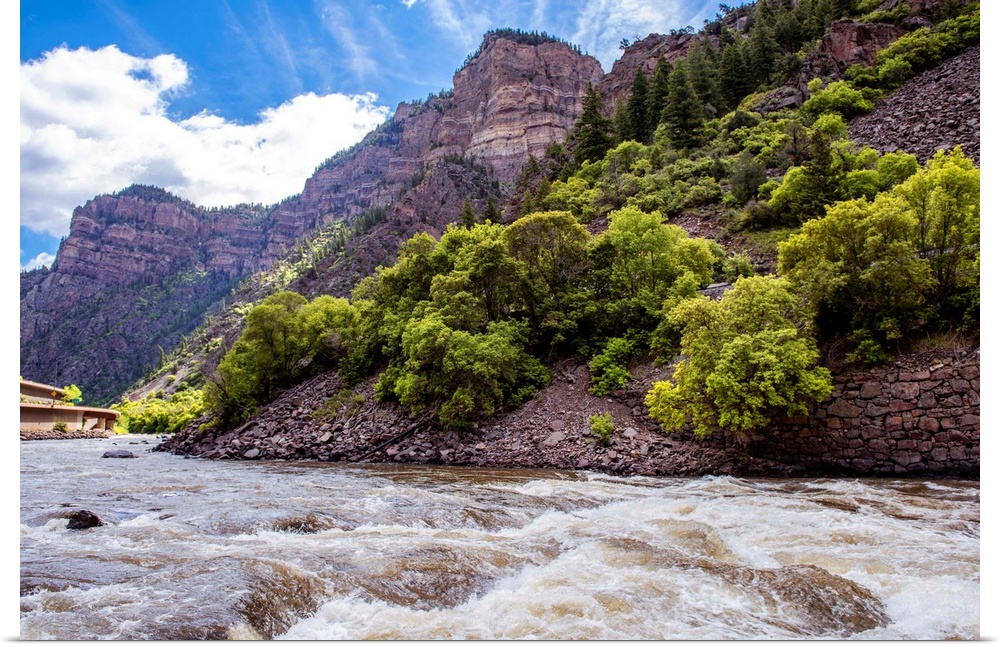 Photo of a rushing river under a mountain cliffside in Colorado.