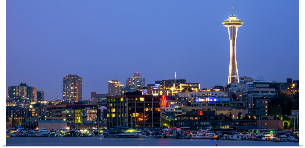 Panoramic photograph of the Seattle skyline lit up at night from the water.