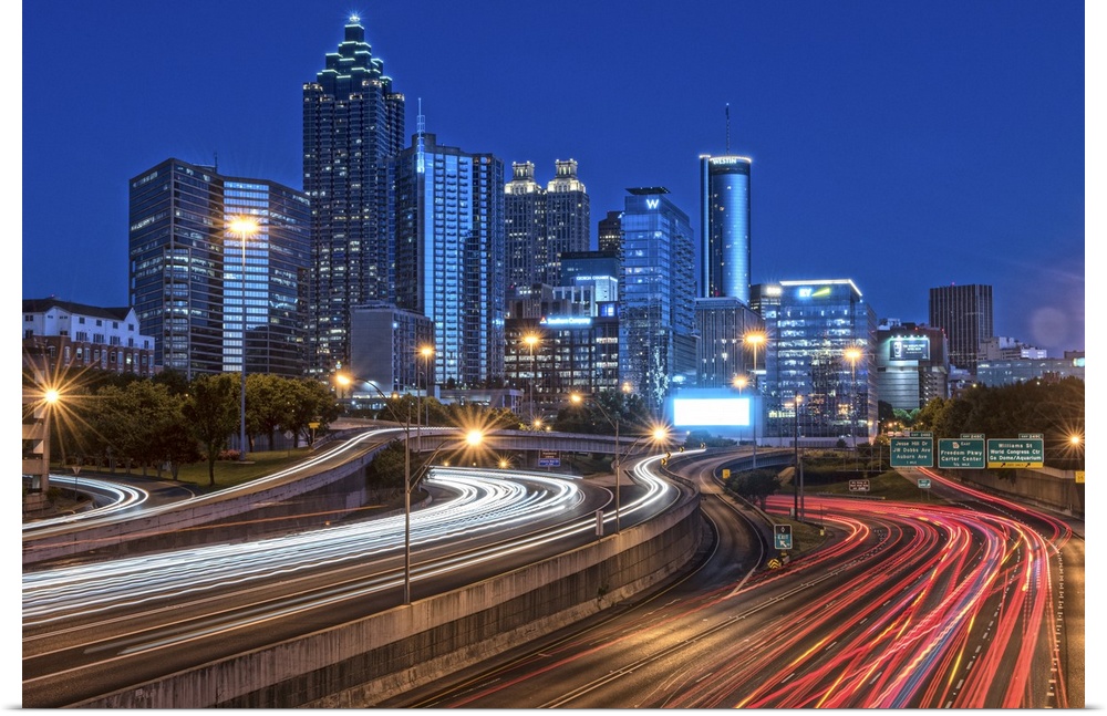 City skyline of Atlanta, Georgia, illuminated night with light trails from passing traffic in the streets.