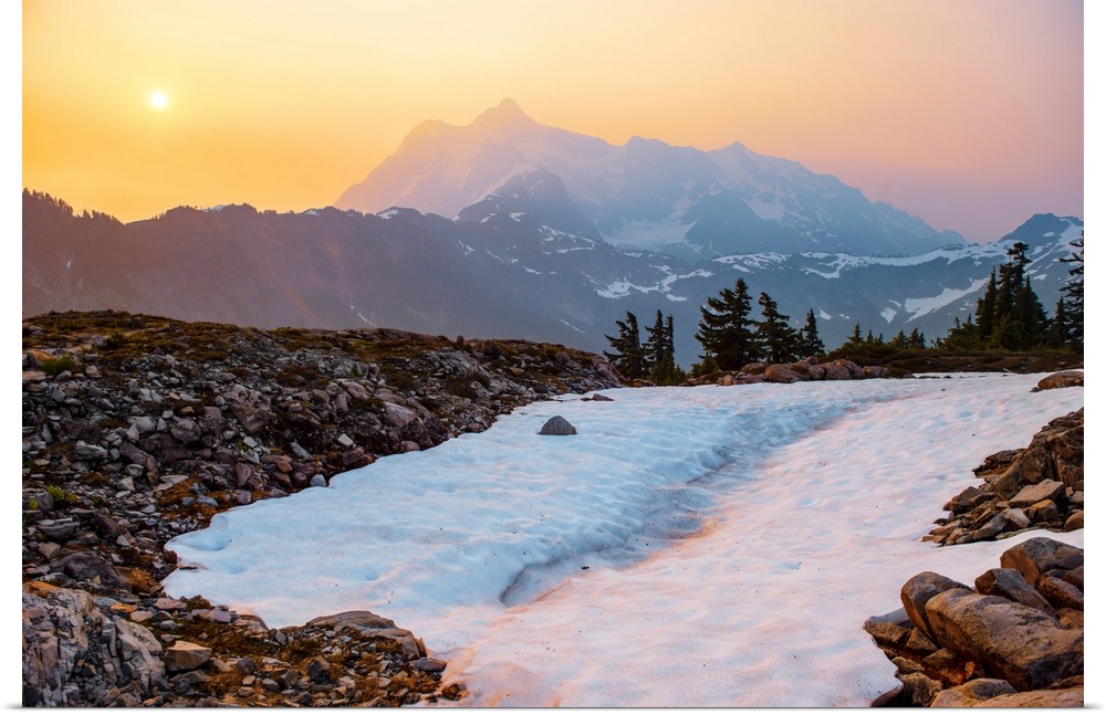 View of a snowy path on Artist Point Trail with the sun rising over Mount Shuksan in the background, Washington.