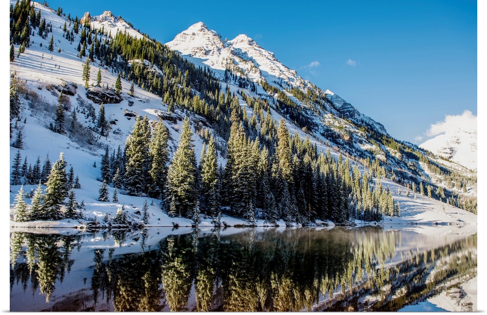 Summer snow on pine trees and the mountain side at the edge of Maroon Lake in the Maroon Bells, Aspen, Colorado.