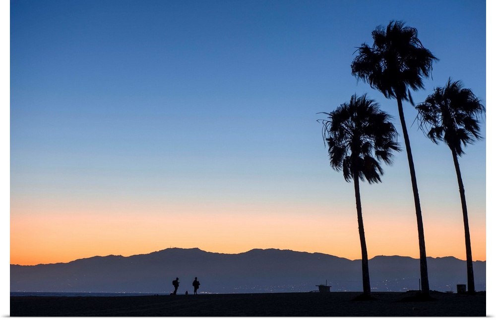 The sun sets on Venice beach with the San Gabriel mountains in the background.