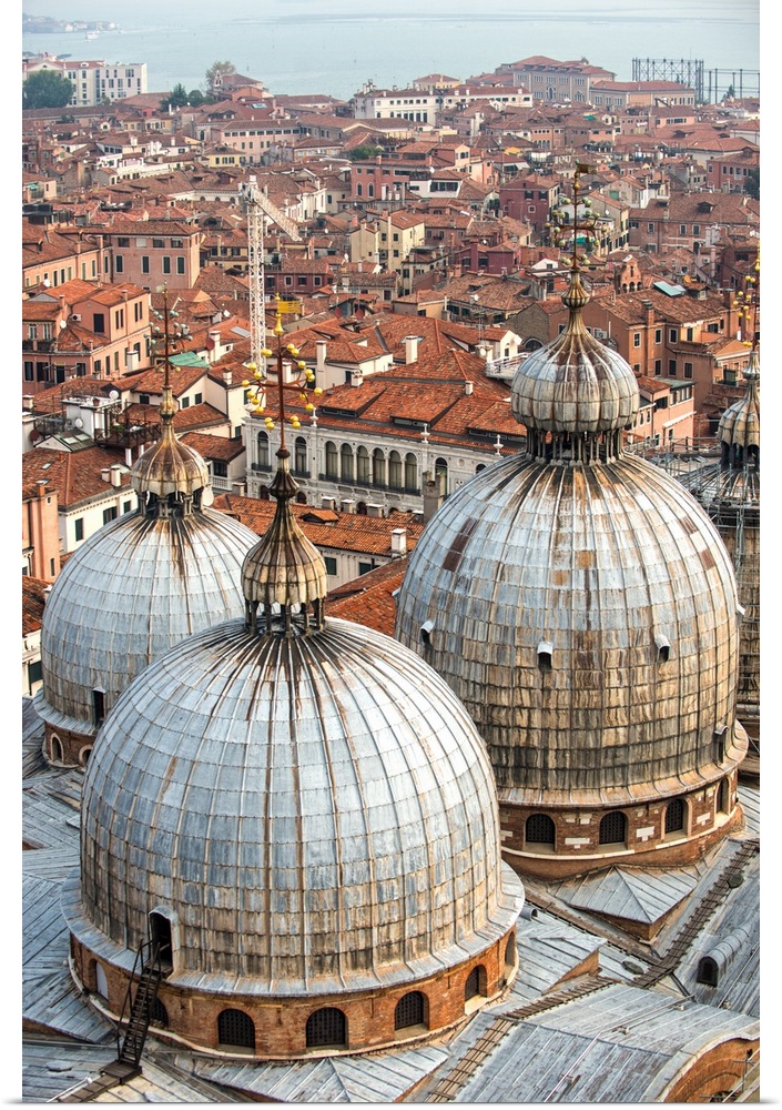 Aerial view of three domes of San Marco Basilica with Venice rooftops in the background.