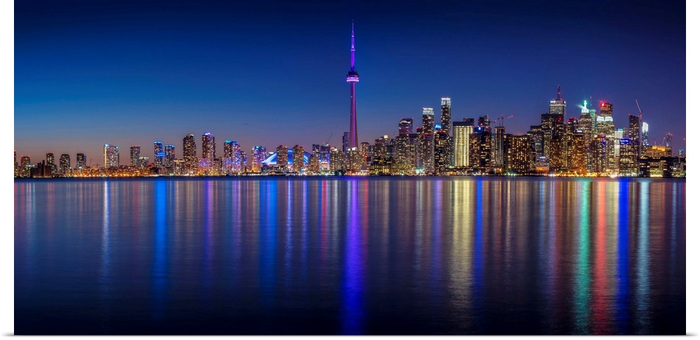 Photo of the Toronto city skyline with lights reflected in the water at night.