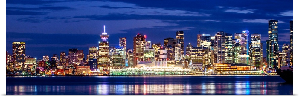 Panoramic photograph of the Vancouver, British Columbia skyline lit up on a dark purple night and reflecting bands of colo...