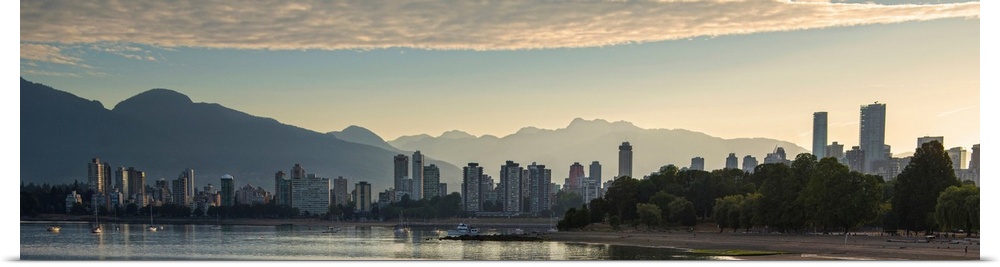 Panoramic photograph of the Vancouver, British Columbia, Canada skyline at sunset with silhouetted mountains in the backgr...