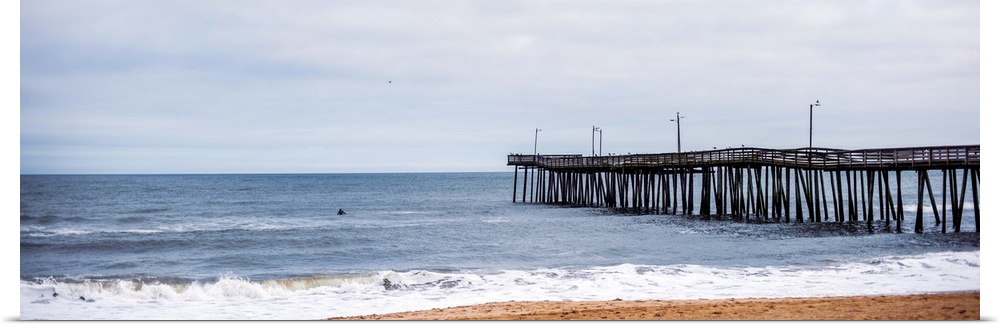 A fishing pier reaches out to the Atlantic ocean while waves crash onto Virginia's sandy beach.