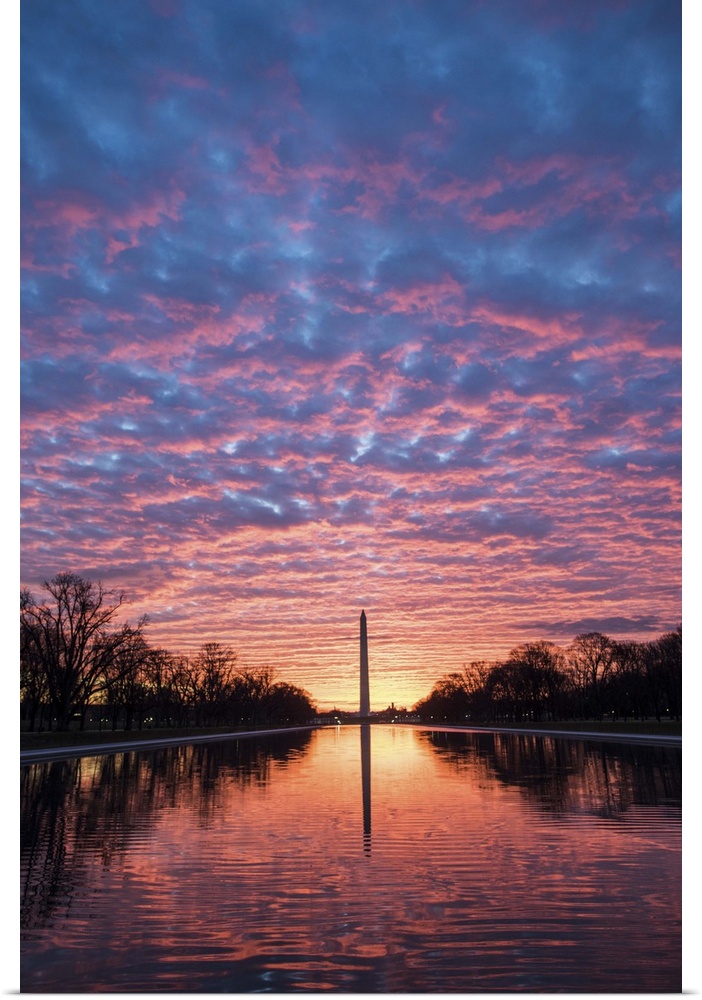 View from the Reflecting Pool of the Washington Monument under dramatic sunset clouds in Washington, DC.