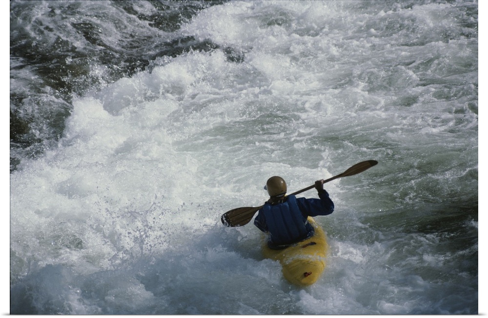 A kayaker paddles through white-water rapids on the Snake River.