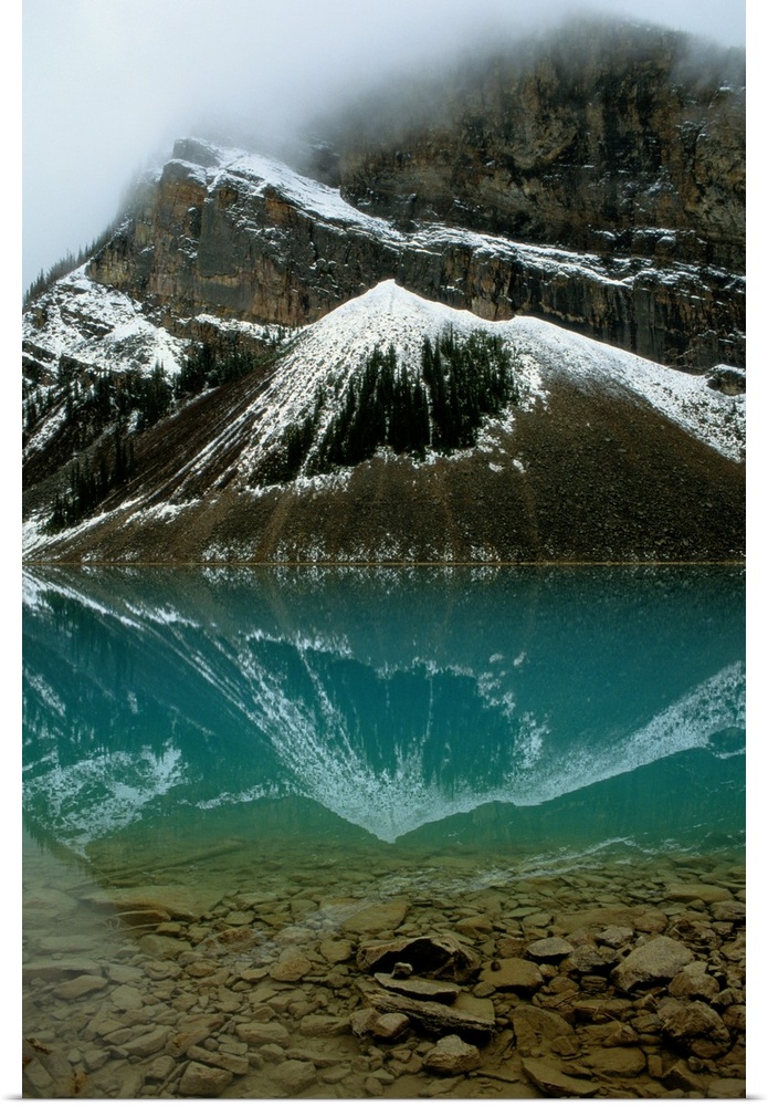 Fog has lifted from Lake Louise and reflections of the snow-capped mountains ar e visible in this glacial lake.