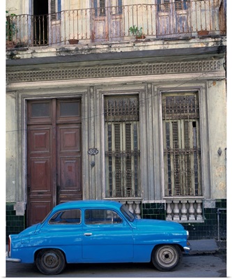 A blue car parked outside a shabby house in Old Havana, Cuba, West Indies
