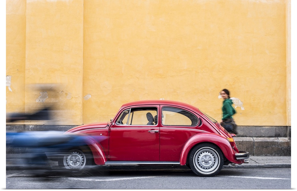 A woman walking past a red VW Beetle in the colourful streets of Popayan, Colombia, South America