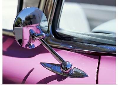 Close-up of a wing mirror and reflection on a pink Cadillac car