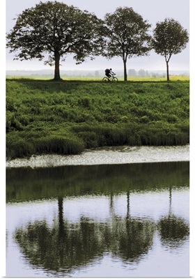 Cyclist on banks of River Somme, St. Valery sur Somme, Picardy, France