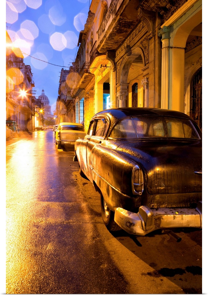 Low light view along a street towards The Capitolio with street lights reflecting in the wet tarmac and wet car bodywork a...