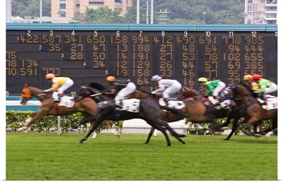 Horses race past large scoreboard during race at Happy Valley racecourse, Hong Kong