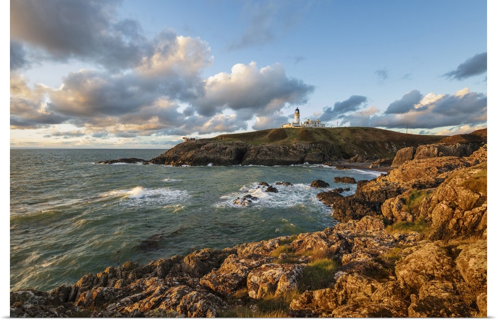Killantringan Lighthouse on Black Head and rocky coastline at sunset, Portpatrick, Dumfries and Galloway, Scotland, United...