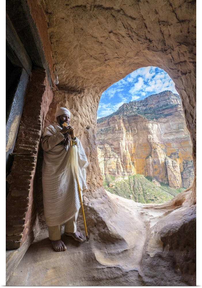 Ethiopian Orthodox priest holding the hand cross at entrance of Abuna Yemata Guh church, Gheralta Mountains, Tigray, Ethio...